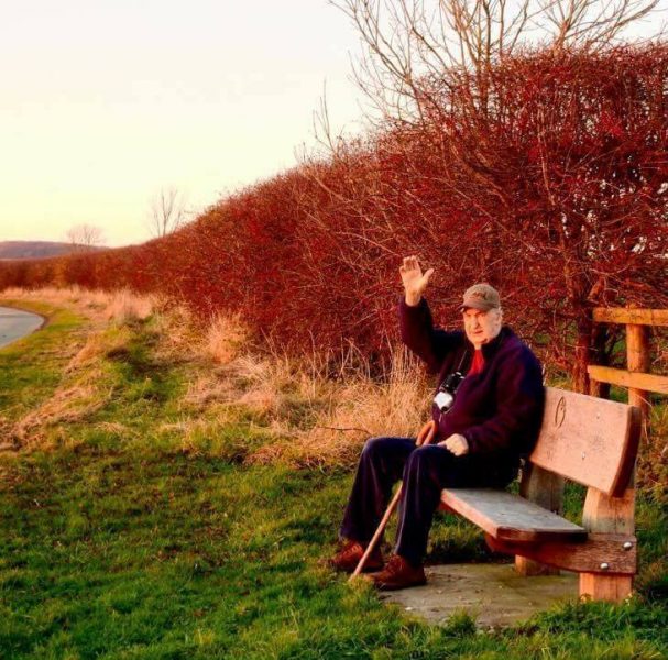 john davison poet sat on a bench waving